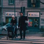 Para z wózkiem przechodzi przez ulicę w centrum dużego miasta
